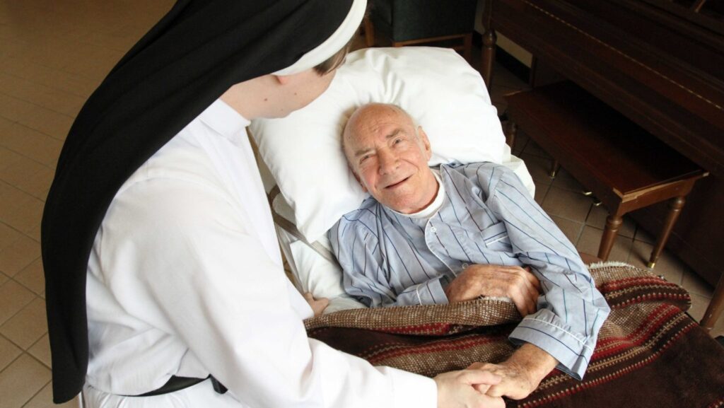 Un paciente conversa con la hermana dominica Catherine Marie en una foto de archivo, en Rosary Hill Home, un centro administrado por las Hermanas Dominicas en Hawthorne, Nueva York, que brinda cuidados paliativos a personas con cáncer incurable y de escasos recursos. Las Hermanas Dominicas de Hawthorne presentaron una demanda contra el estado de Nueva York para impugnar una ley estatal que exige a los centros de atención a largo plazo utilizar los pronombres preferidos de los pacientes y asignar las habitaciones según la identidad de género. (Foto de OSV News/Gregory A. Shemitz)